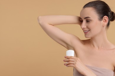 Photo of Beautiful woman applying deodorant on beige background, space for text