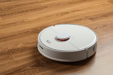 Photo of Robotic vacuum cleaner on wooden floor, space for text