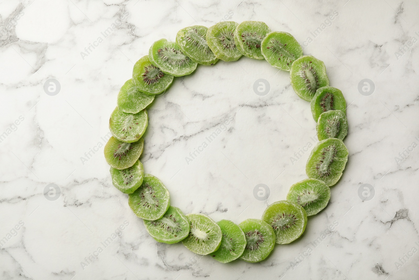 Photo of Frame made of kiwi on marble background, top view with space for text. Dried fruit as healthy food