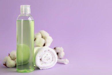 Photo of Cotton swabs, towel, dry flowers and makeup removal product on violet background. Space for text