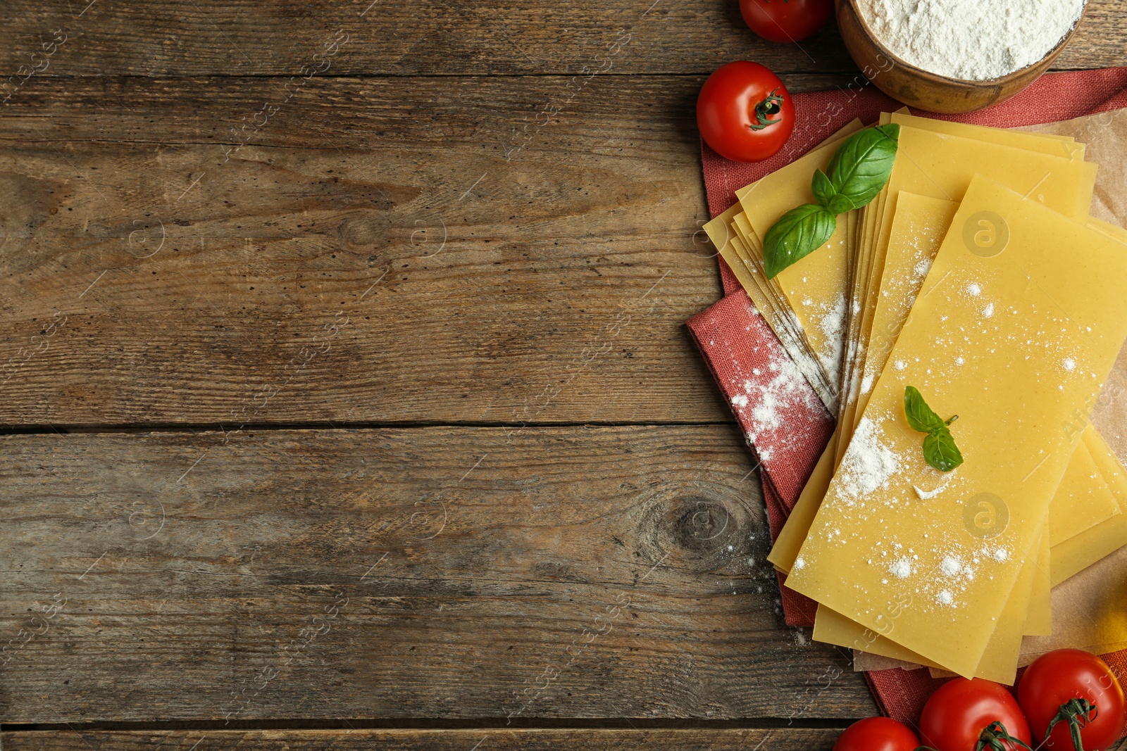 Photo of Flat lay composition with uncooked lasagna sheets on wooden table. Space for text