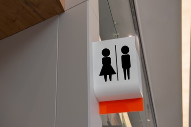 Image of White public toilet sign hanging on wall indoors