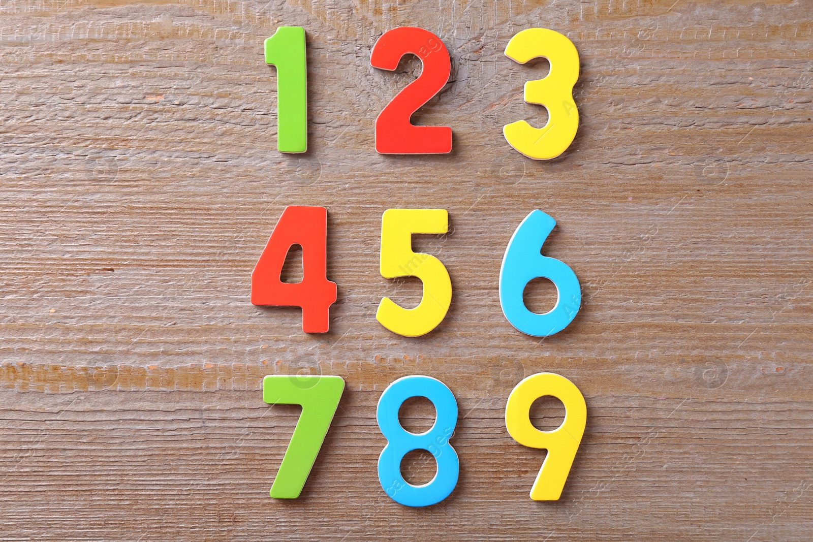 Photo of Colorful numbers on wooden table, flat lay