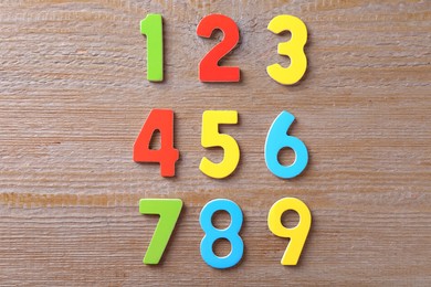 Photo of Colorful numbers on wooden table, flat lay