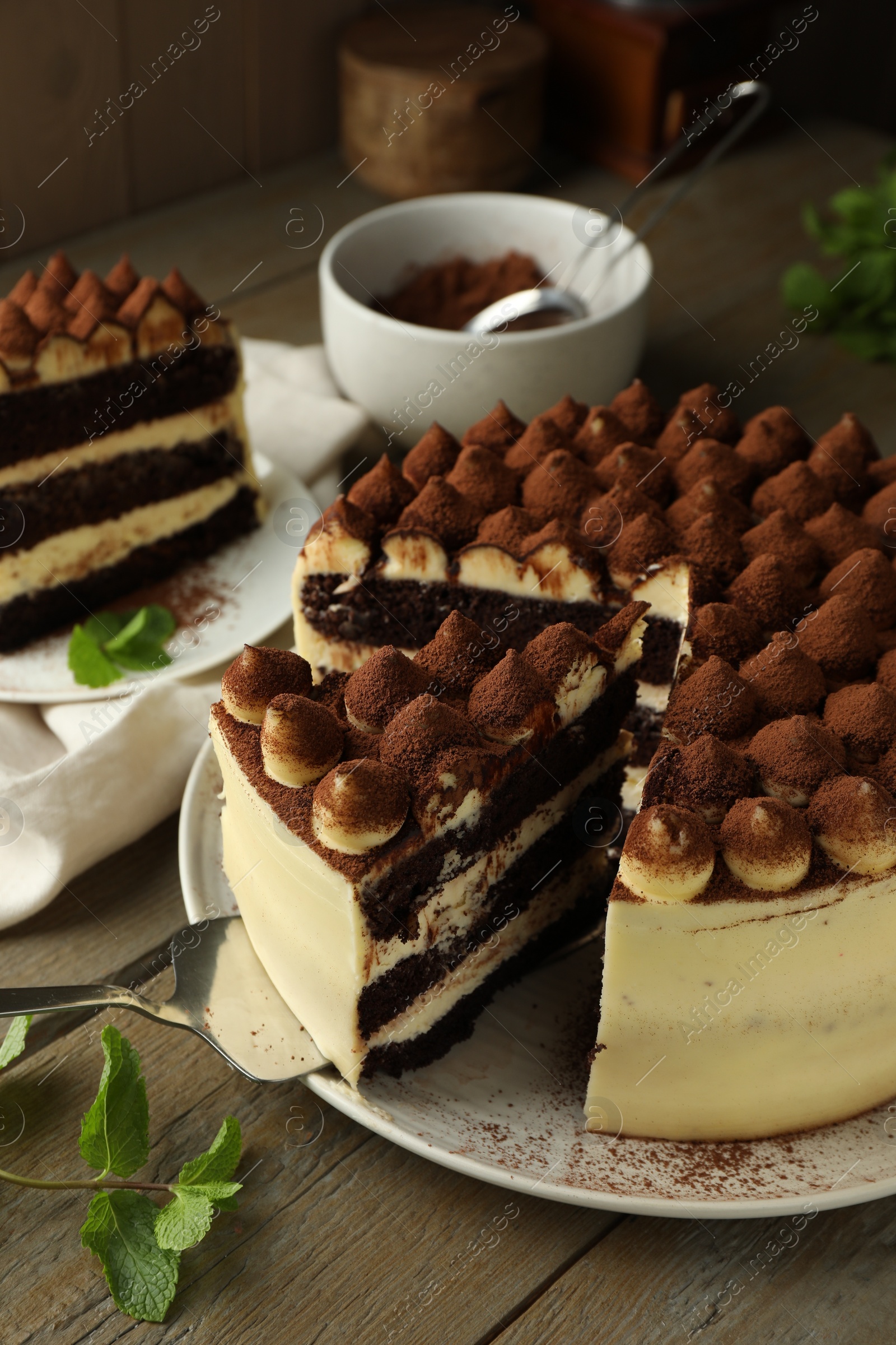 Photo of Delicious tiramisu cake with mint leaves on wooden table