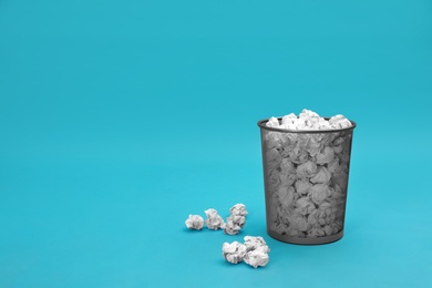 Photo of Metal bin with crumpled paper on color background, space for text