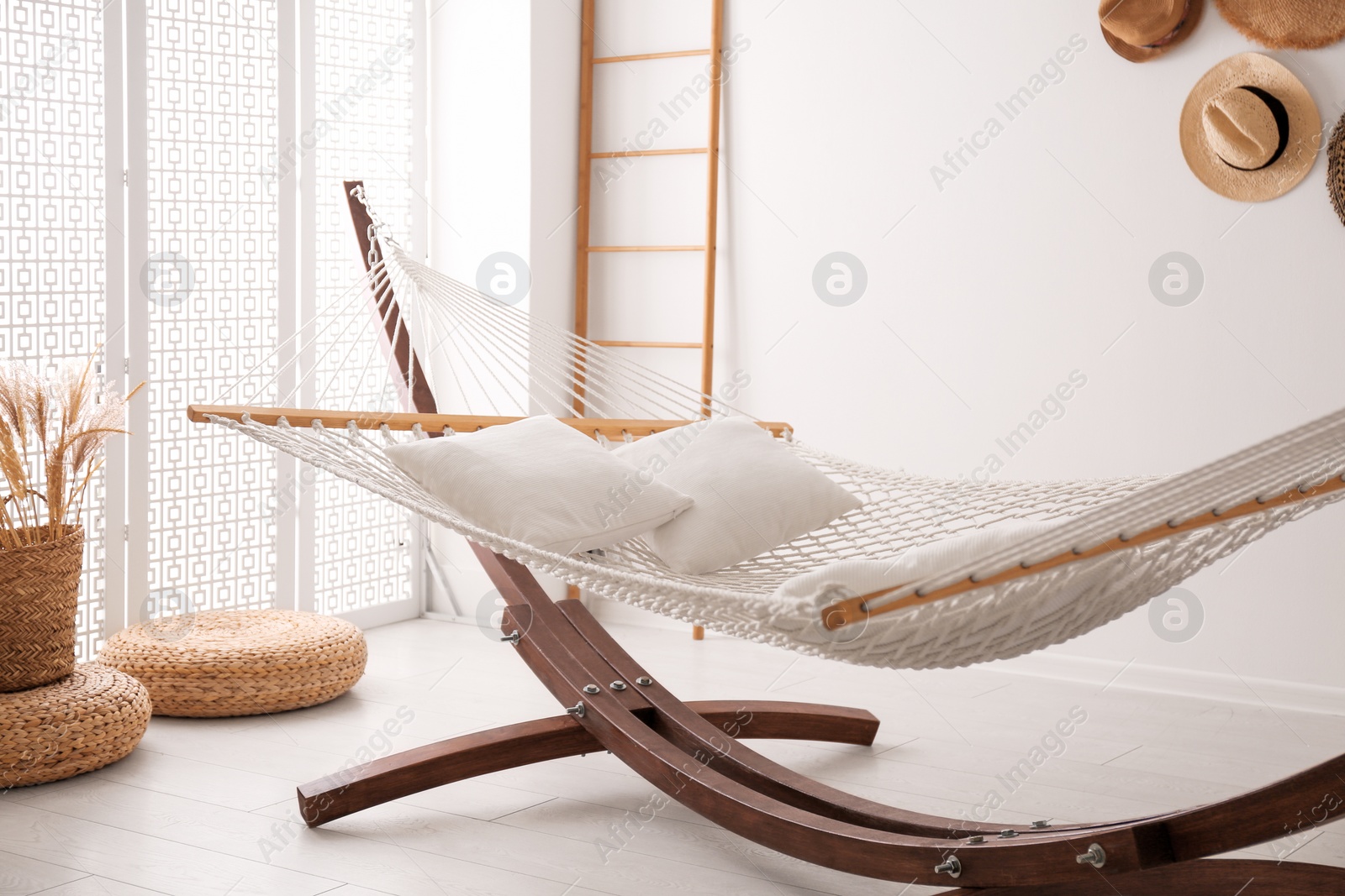 Photo of Comfortable hammock with pillows in stylish room. Interior design