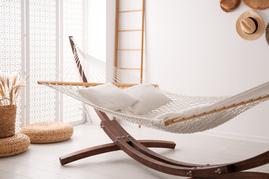 Comfortable hammock with pillows in stylish room. Interior design