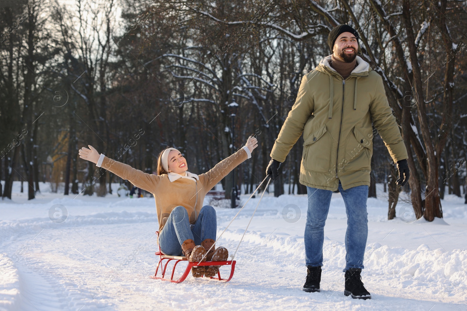 Photo of Man pulling his girlfriend in sleigh outdoors on winter day