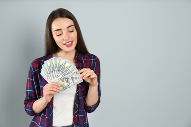 Photo of Young woman with money on light grey background. Space for text