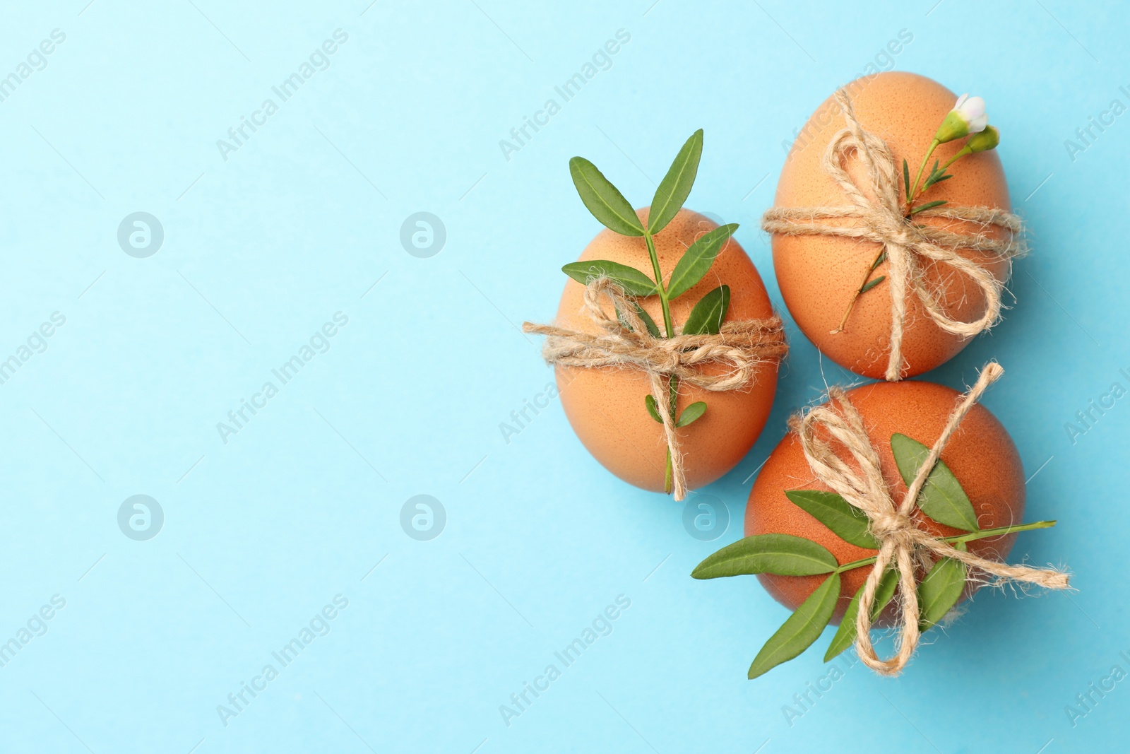 Photo of Festively decorated chicken eggs on light blue background, flat lay with space for text. Happy Easter