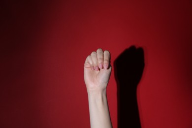 SOS gesture. Woman showing signal for help on red background, closeup