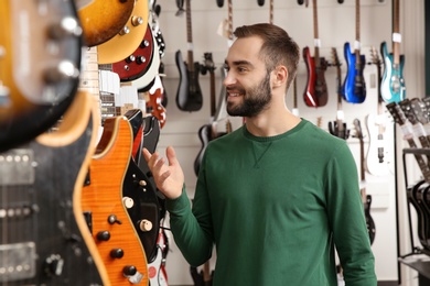 Photo of Buyer choosing guitar in modern music store