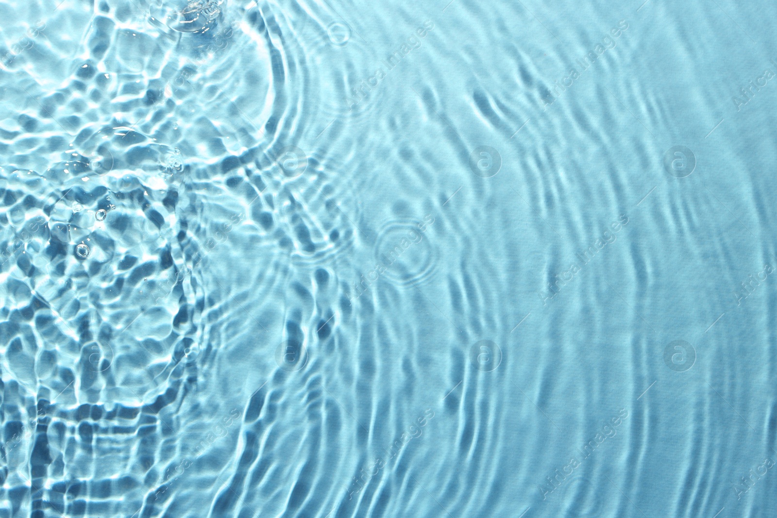 Image of Rippled surface of clear water on light blue background, top view