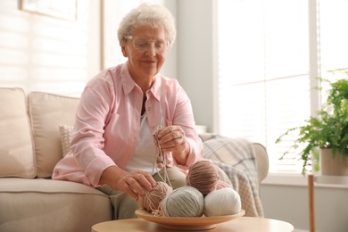 Photo of Elderly woman knitting at home. Creative hobby