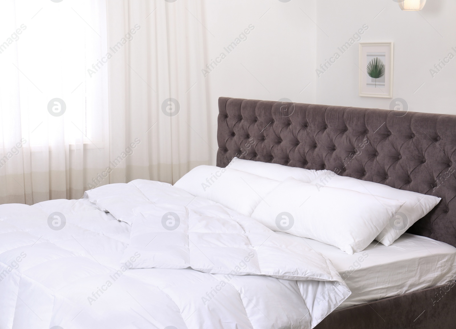 Photo of Large comfortable bed in light room. Stylish interior