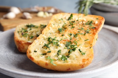 Photo of Plate with delicious homemade garlic bread on table