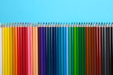 Photo of Colorful pencils on light blue background, flat lay