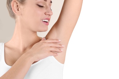 Young woman showing armpit on color background, space for text. Using deodorant