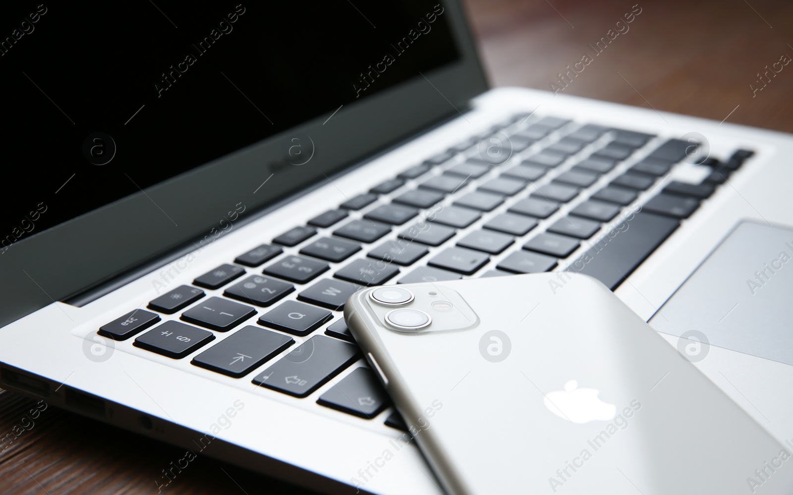 Photo of MYKOLAIV, UKRAINE - JULY 20, 2020: iPhone 11 and MacBook on wooden table, closeup