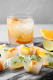 Photo of Ice cubes with orange and mint on table, closeup
