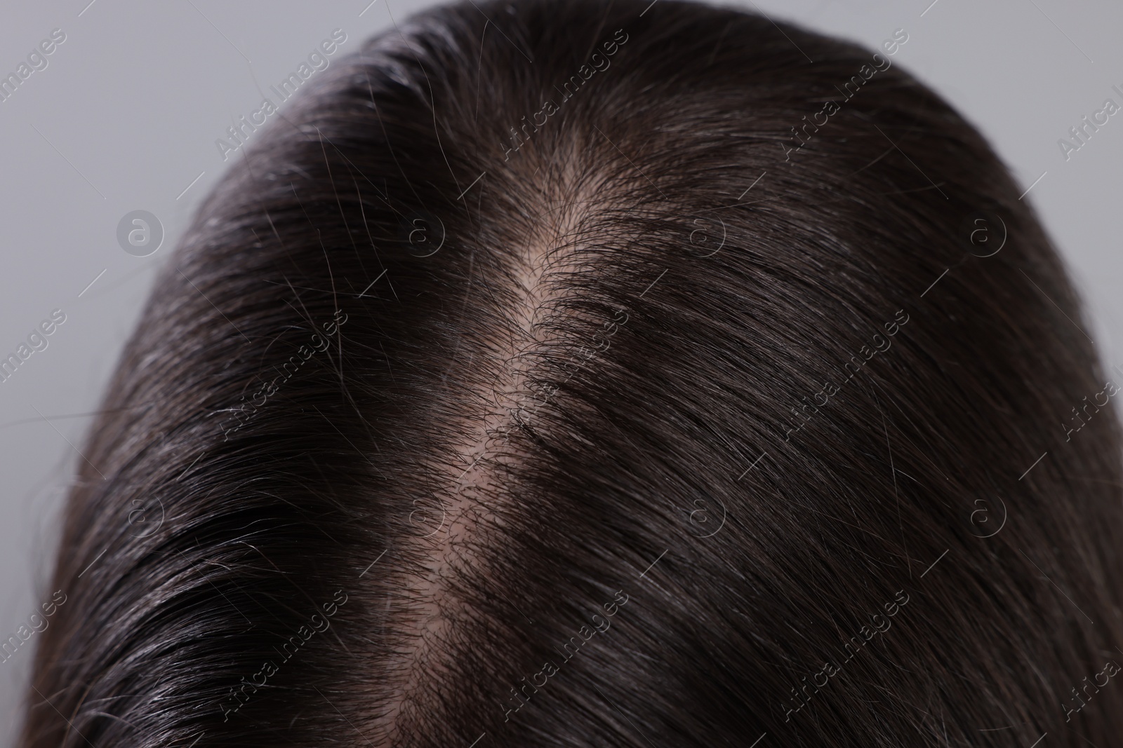 Photo of Closeup view of healthy woman`s hair on grey background
