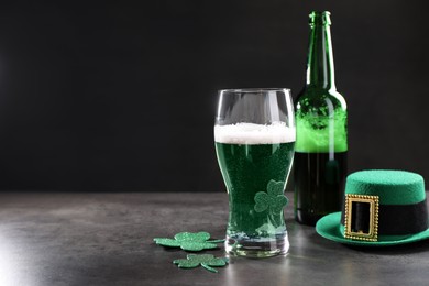 Photo of St. Patrick's day celebration. Green beer, leprechaun hat and decorative clover leaves on grey table. Space for text