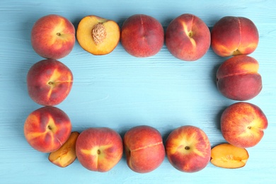 Photo of Frame made of fresh peaches on blue wooden table, top view with space for text