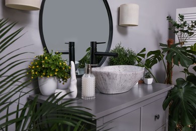 Stylish sink and beautiful green houseplants in bathroom. Interior design