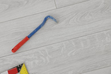 Nail puller on laminate flooring, top view. Space for text