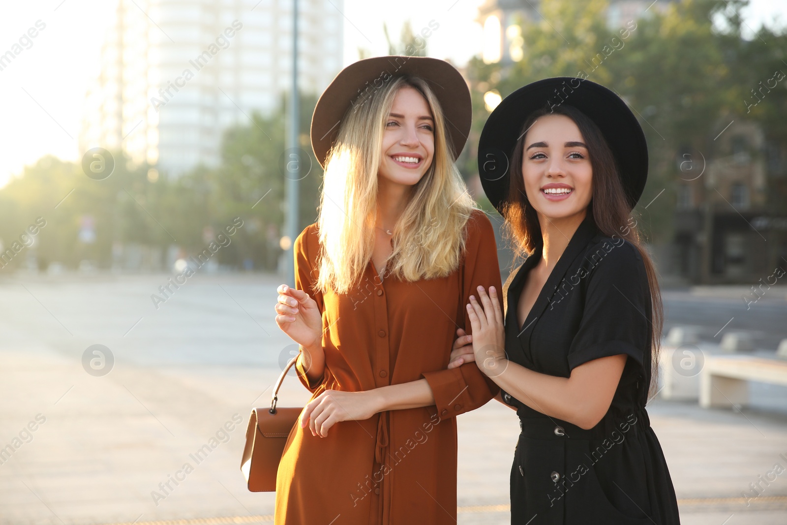 Photo of Beautiful young women in stylish dresses on city street