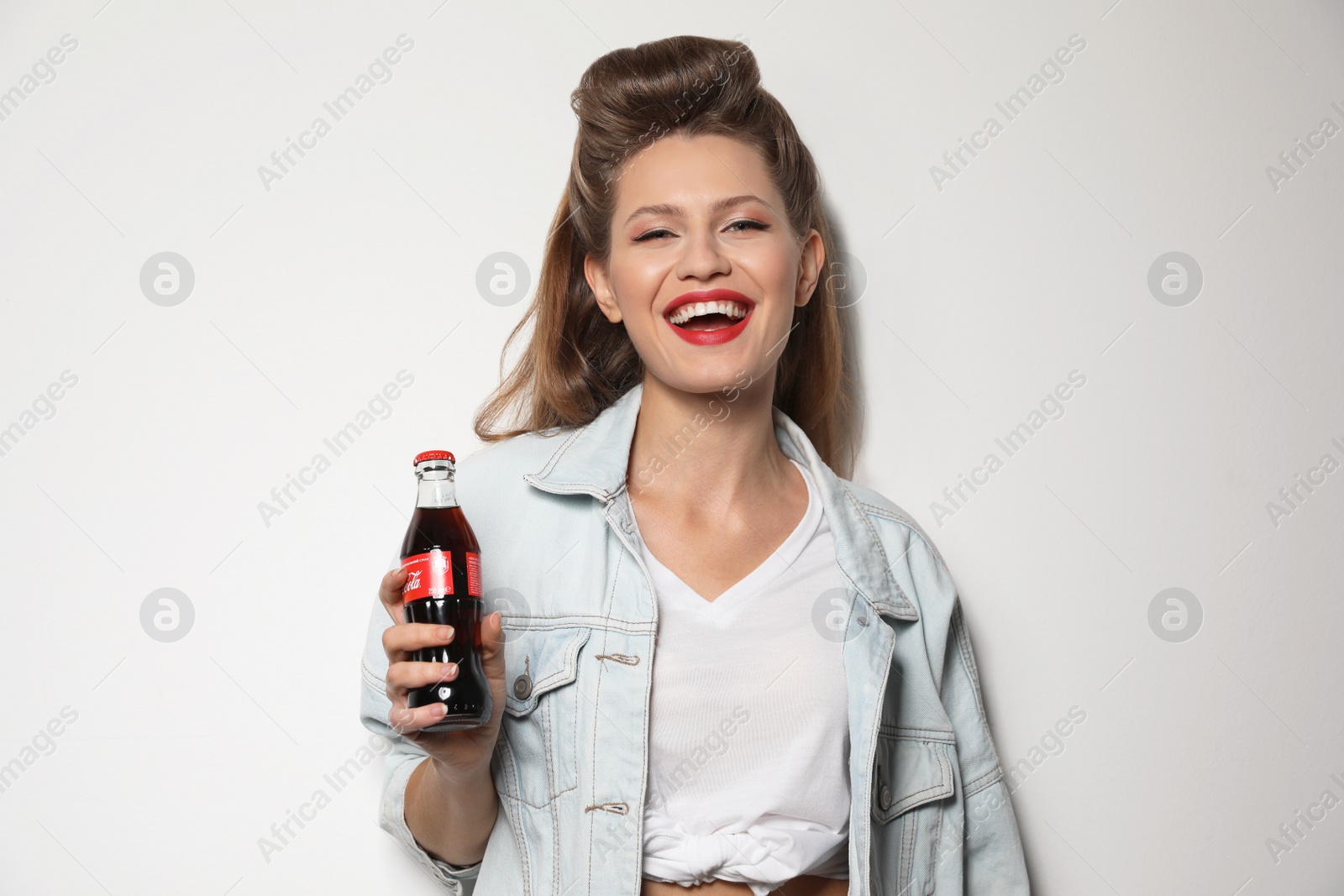 Photo of MYKOLAIV, UKRAINE - NOVEMBER 28, 2018: Young woman with bottle of Coca-Cola on white background