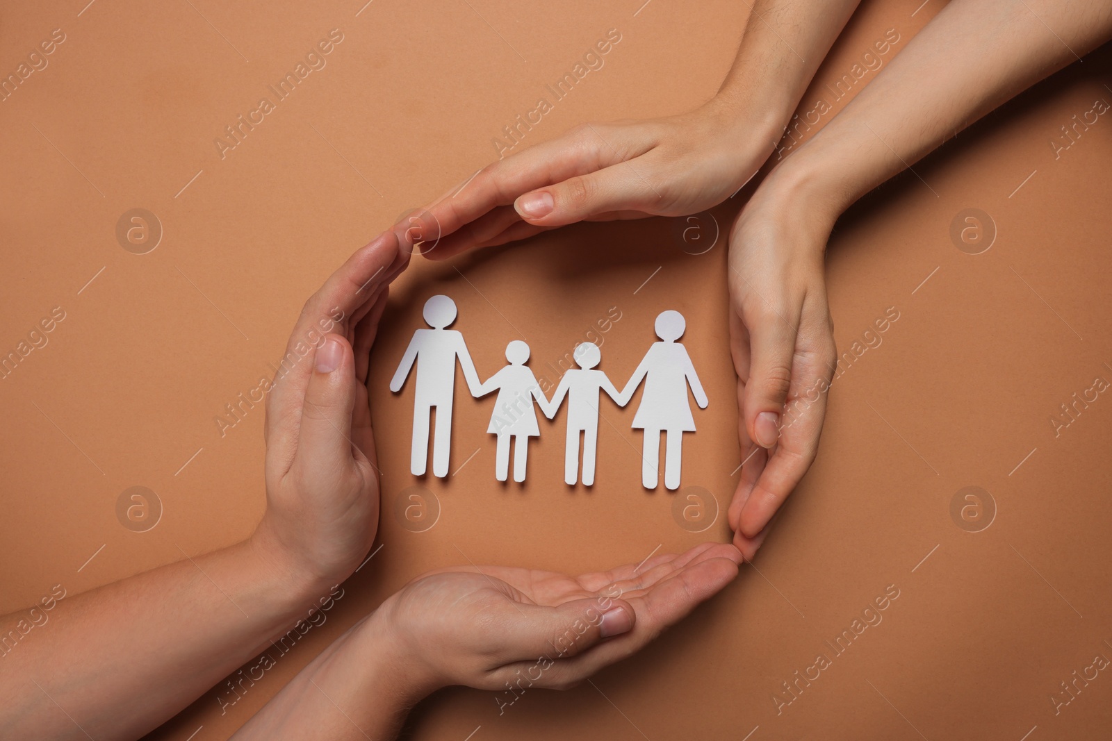 Photo of Couple protecting paper family figures on brown background, top view. Insurance concept