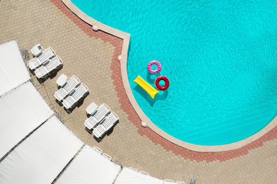 Inflatable rings and mattress floating in swimming pool, top view. Summer vacation