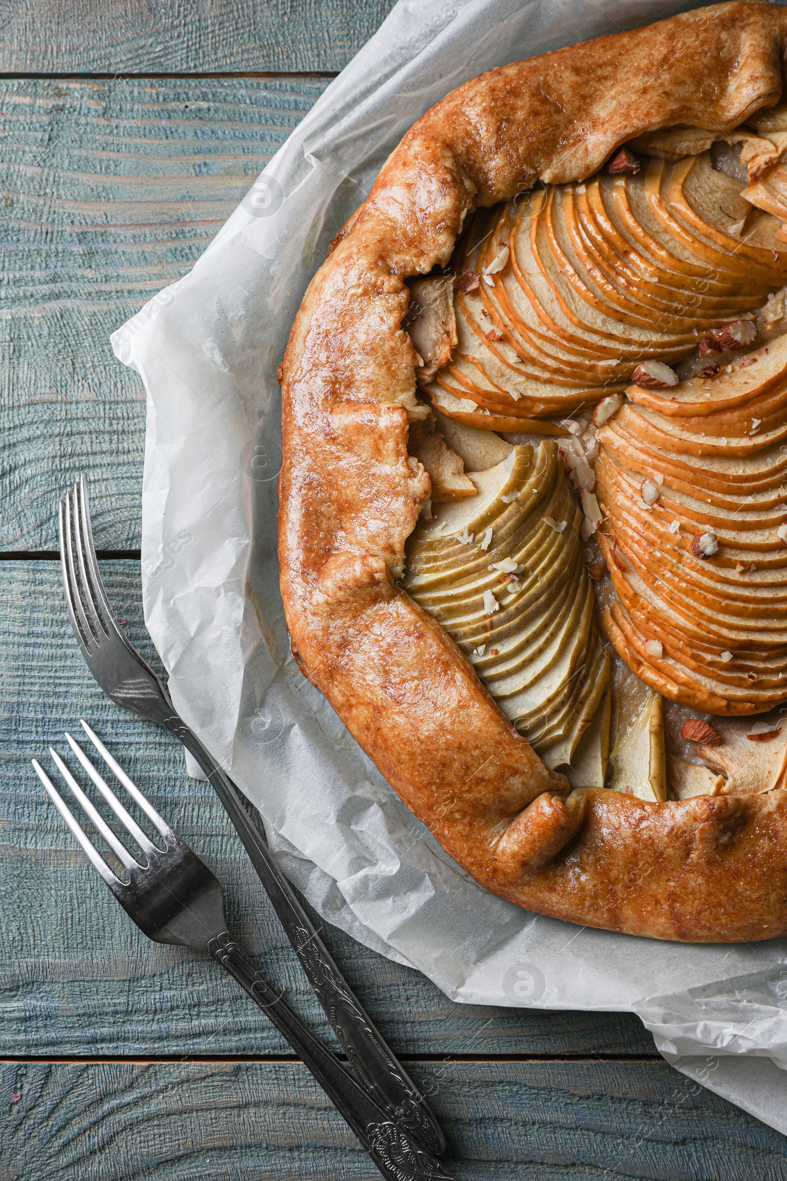Photo of Delicious apple galette with walnuts and forks on wooden table, flat lay