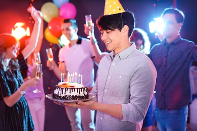 Photo of Young man with birthday cake at party in nightclub