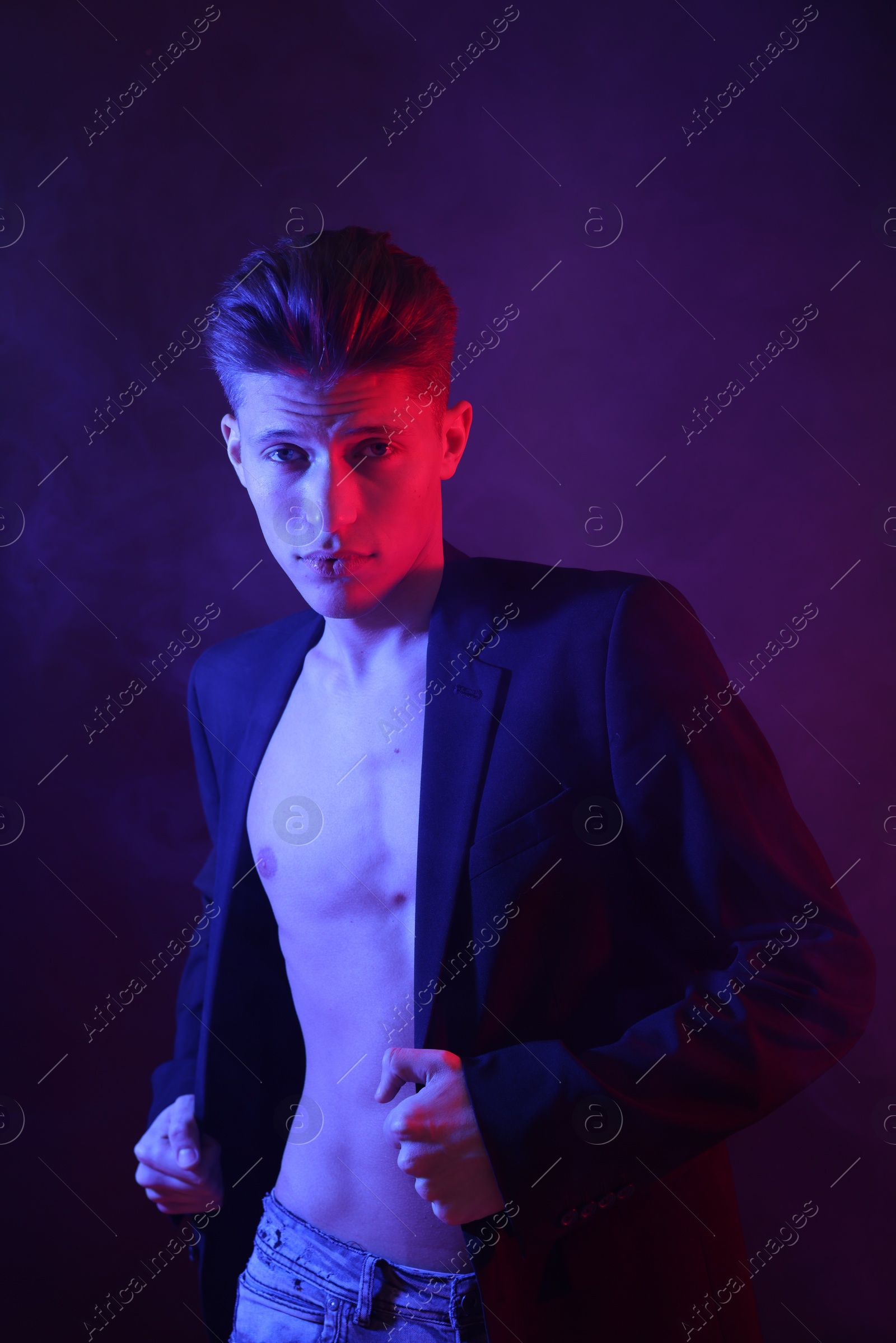 Photo of Sexy young man on dark background in neon lights