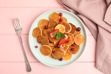 Photo of Cereal pancakes with berries served on pink wooden table, flat lay