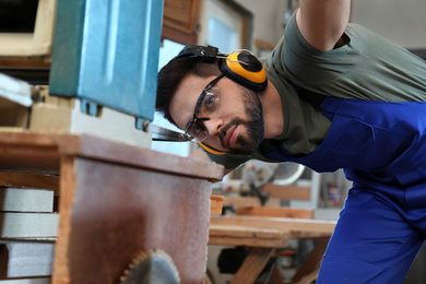 Photo of Professional carpenter working with grinding machine in shop