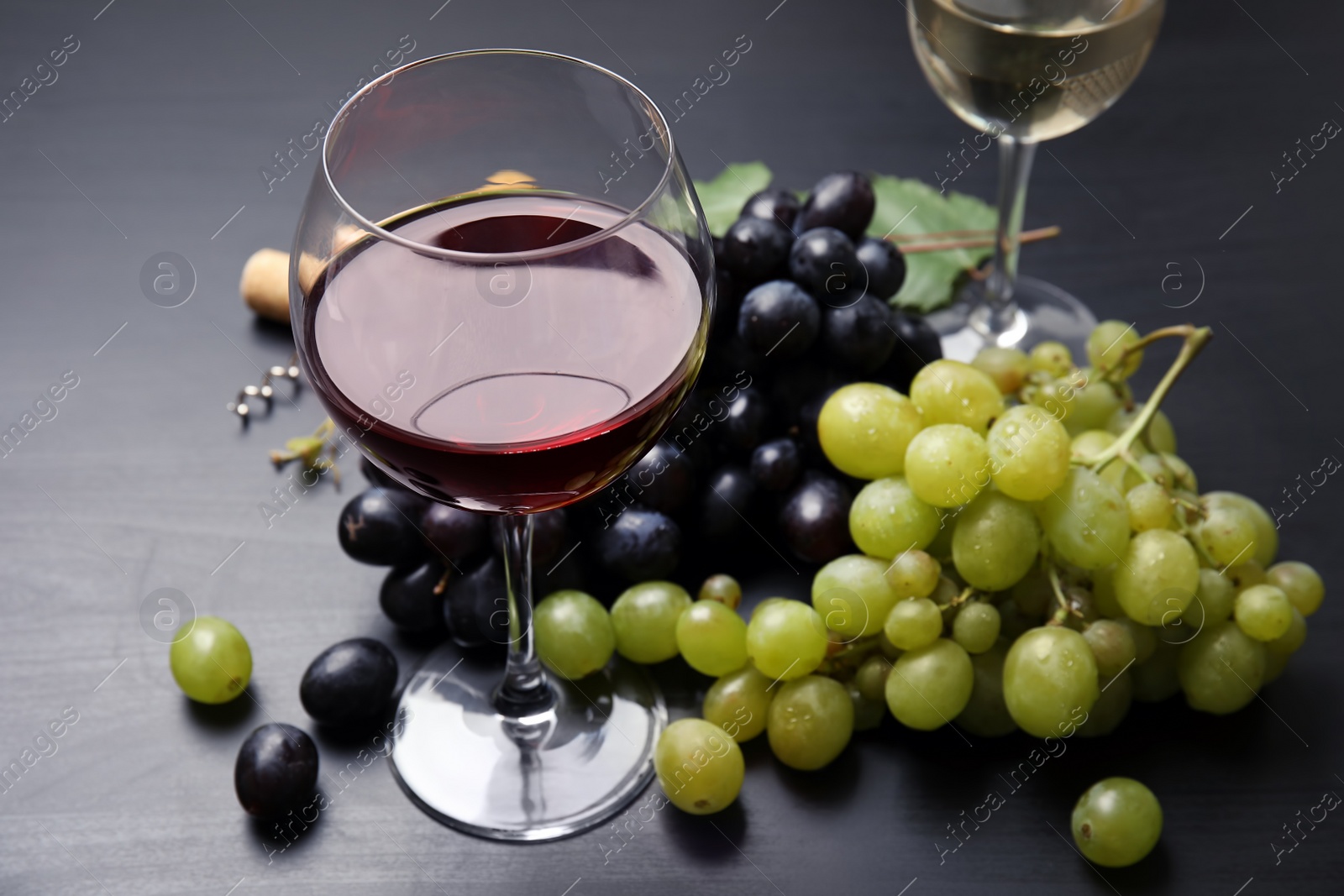 Photo of Glass of red wine and fresh ripe juicy grapes on table