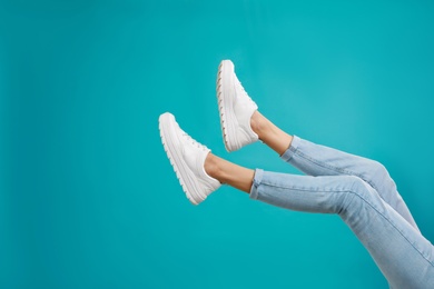 Photo of Woman in stylish sport shoes on light blue background