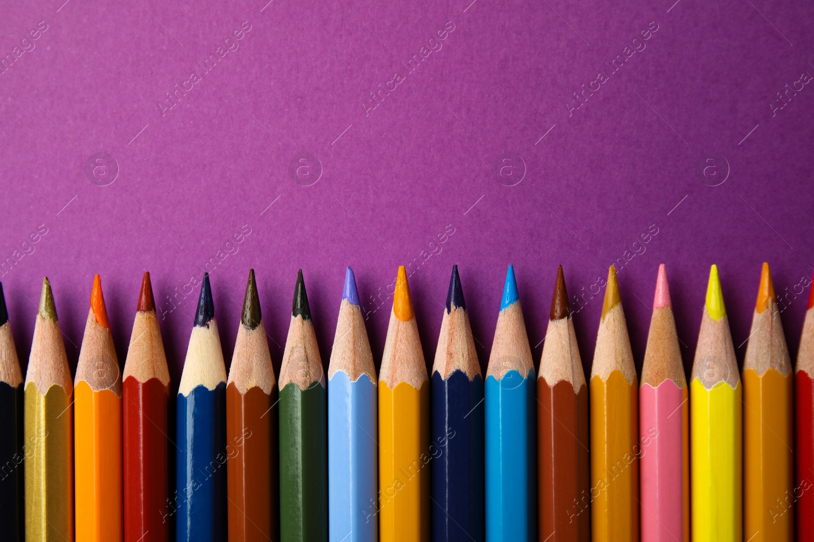 Photo of Flat lay composition with color pencils on purple background. Space for text