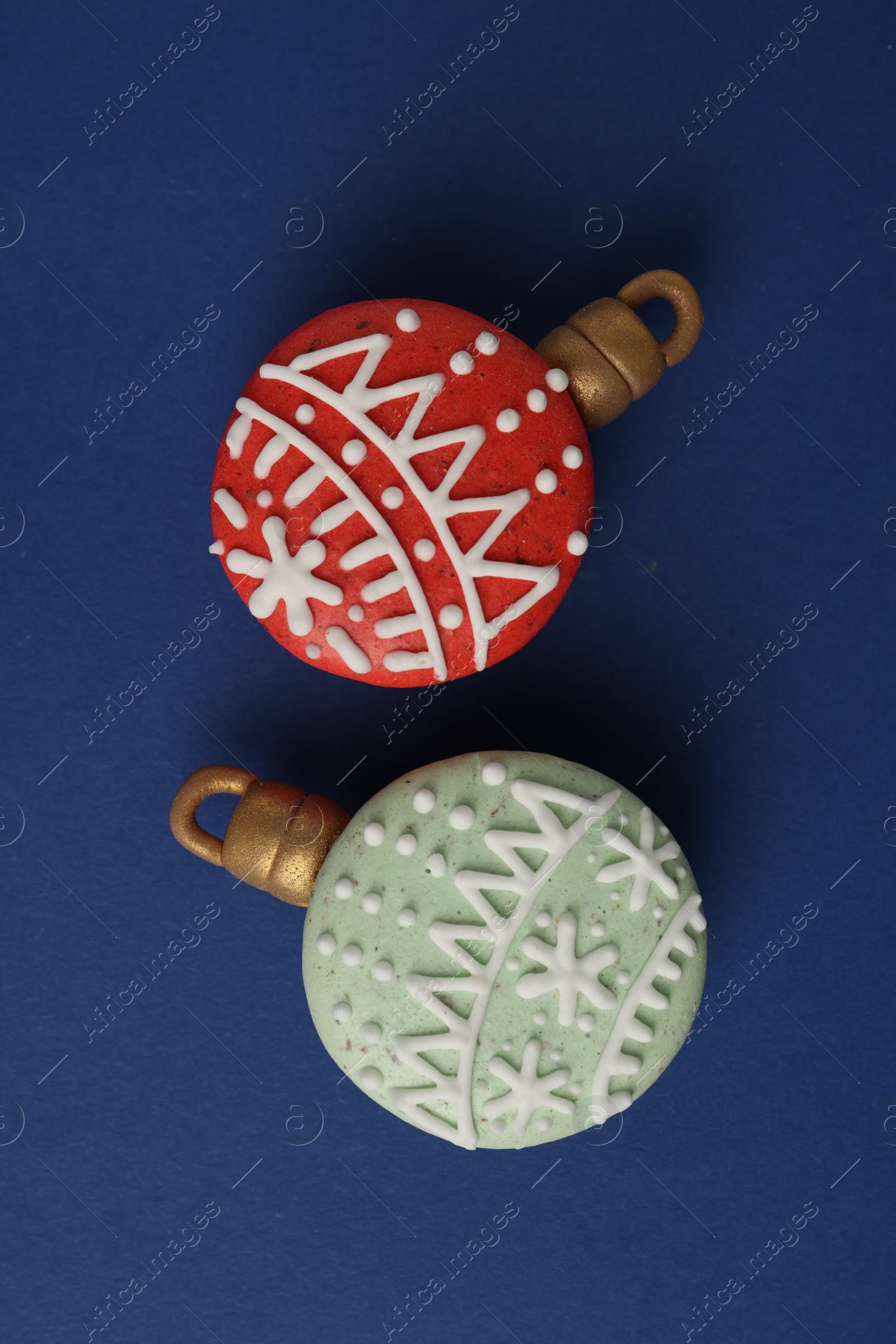 Photo of Beautifully decorated Christmas macarons on blue background, flat lay