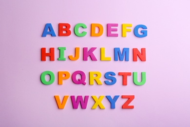 Colorful magnetic letters on violet background, flat lay. Alphabetical order