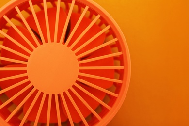 Bright portable fan on orange background, top view