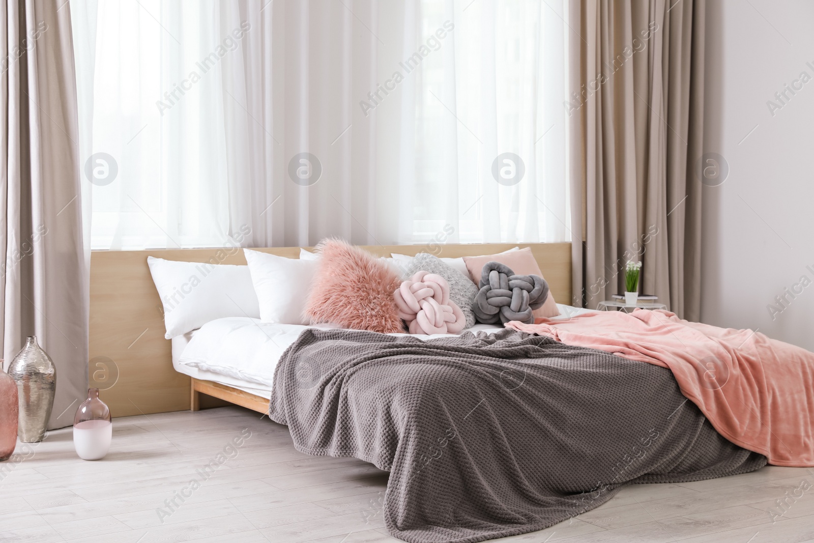 Photo of Comfortable bed with pillows and plaid in modern room interior