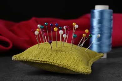 Photo of Yellow cushion with pins on grey stone table, closeup