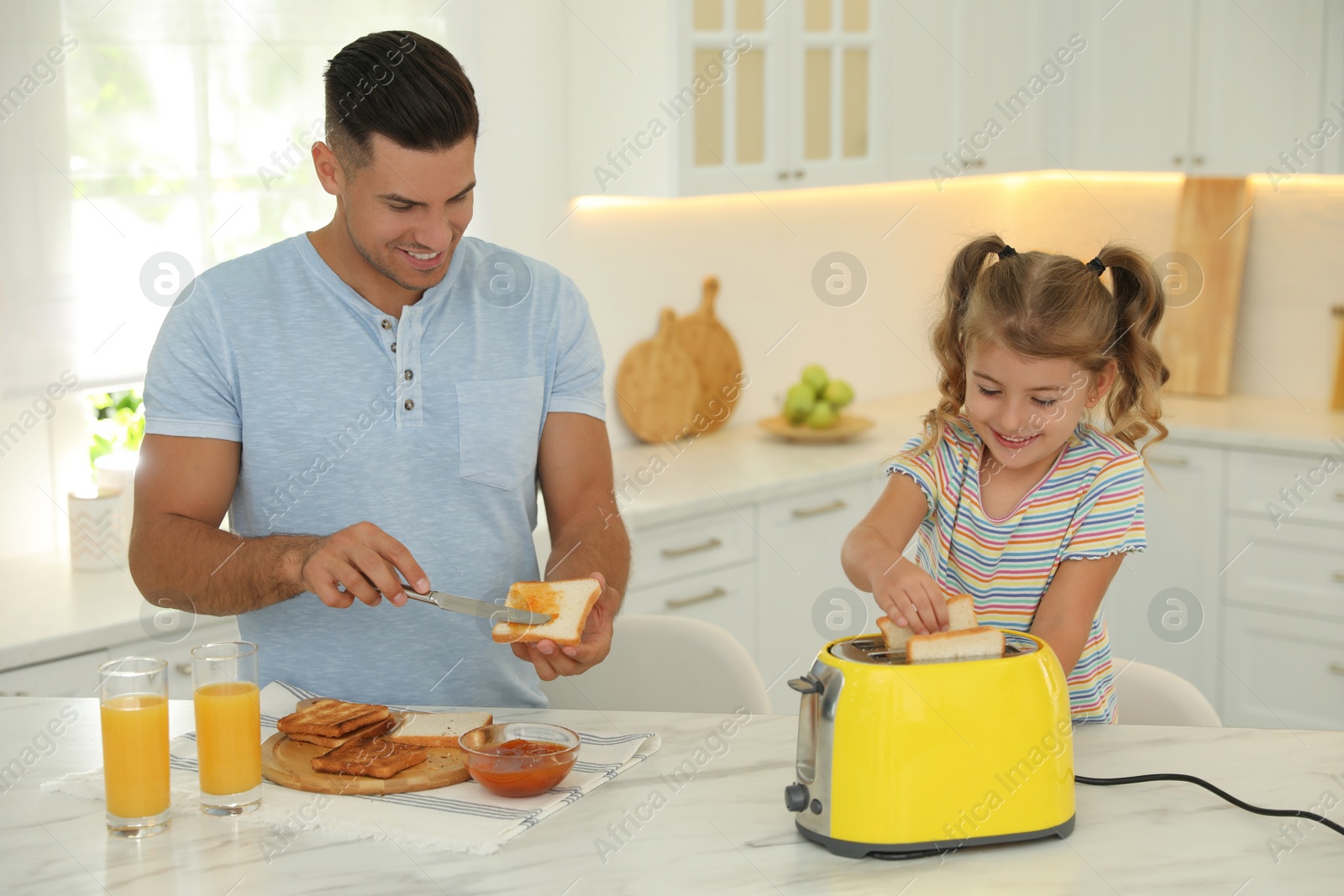 Photo of Father and daughter preparing sandwiches 
using modern toaster at table in kitchen