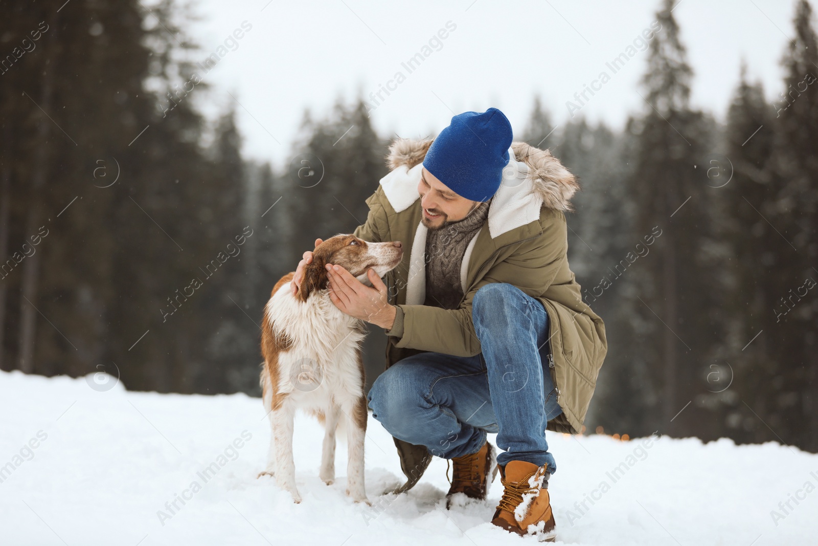 Photo of Man with cute dog near forest. Winter vacation