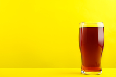 Photo of Delicious homemade kvass in glass on yellow background. Space for text